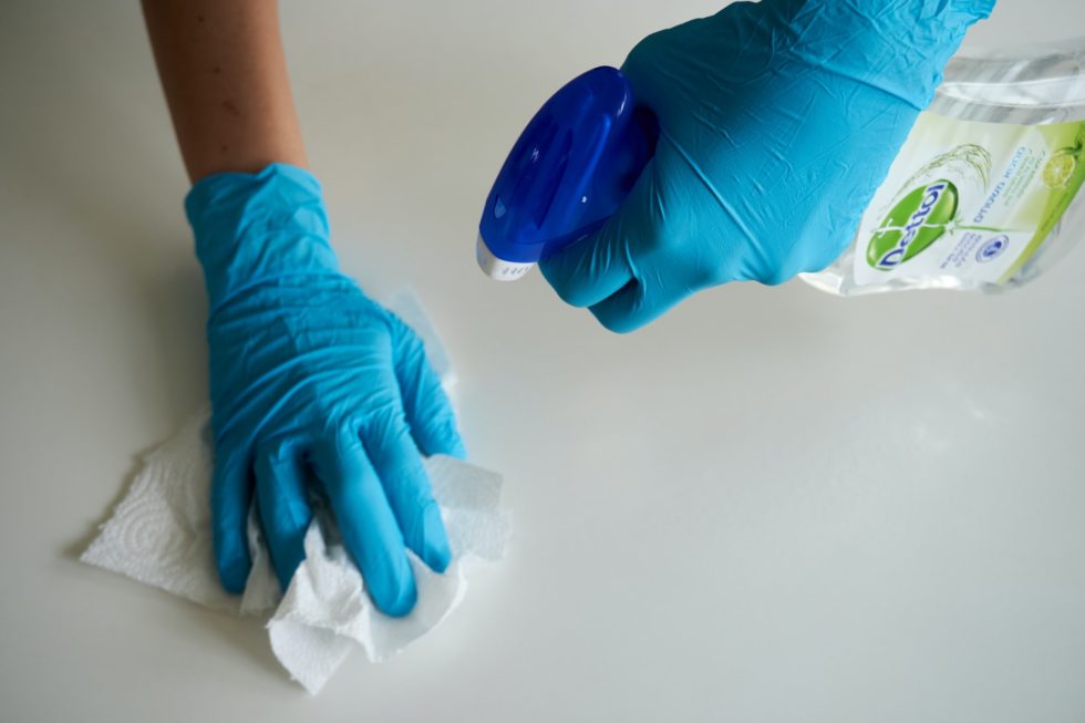 a clenercleaning table with both hands covering with gloves