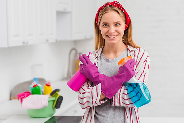 empregada profissional segurando detergentes de limpeza e pronta para limpar
